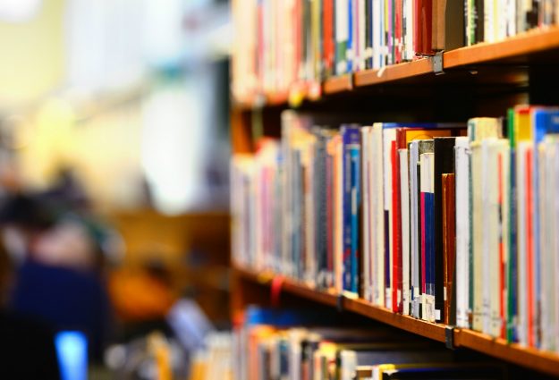 An image of a library, with bookshelves and people in the background