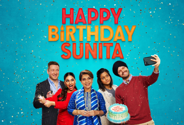 A modern family of five, with mum in the middle, of south Asian / Sikh heritage. They are facing us, posing for a selfie, one holding up a mobile phone, another a birthday cake. They're in front of a bright blue background with confetti and 'Happy Birthday Sunita' written in big bright letters the background. Most are smiling, except for a young women who looks grumpy (I think that might be Sunita!)